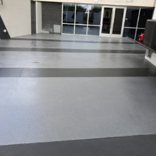 Striped gray epoxy floor leading to glass doors